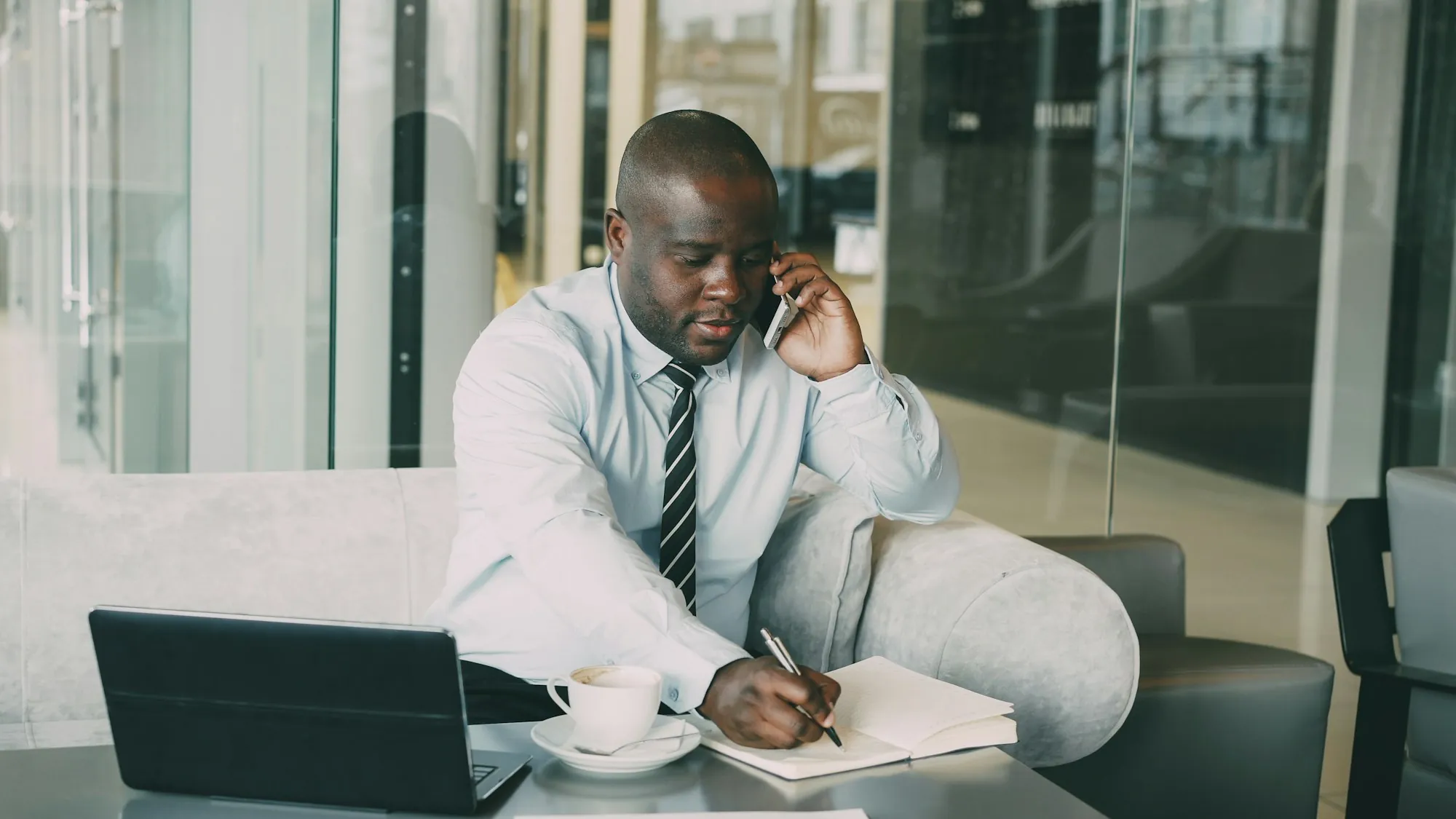 Someone taking notes on a pad while talking on the phone at a desk