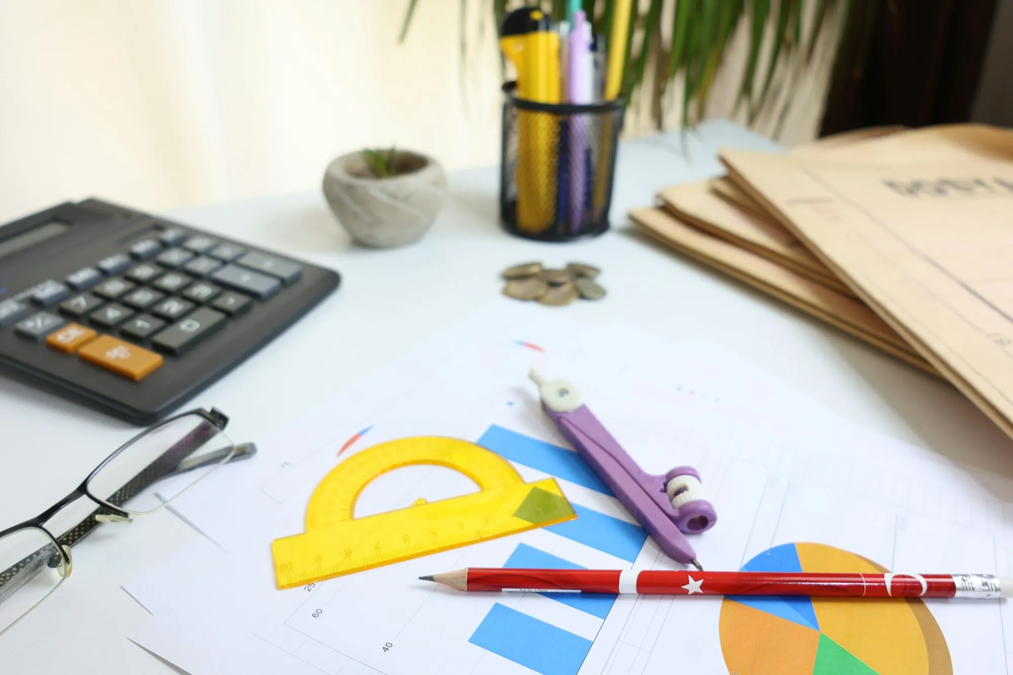 A tidy desk with a notebook, a pencil and a pair of reading glasses