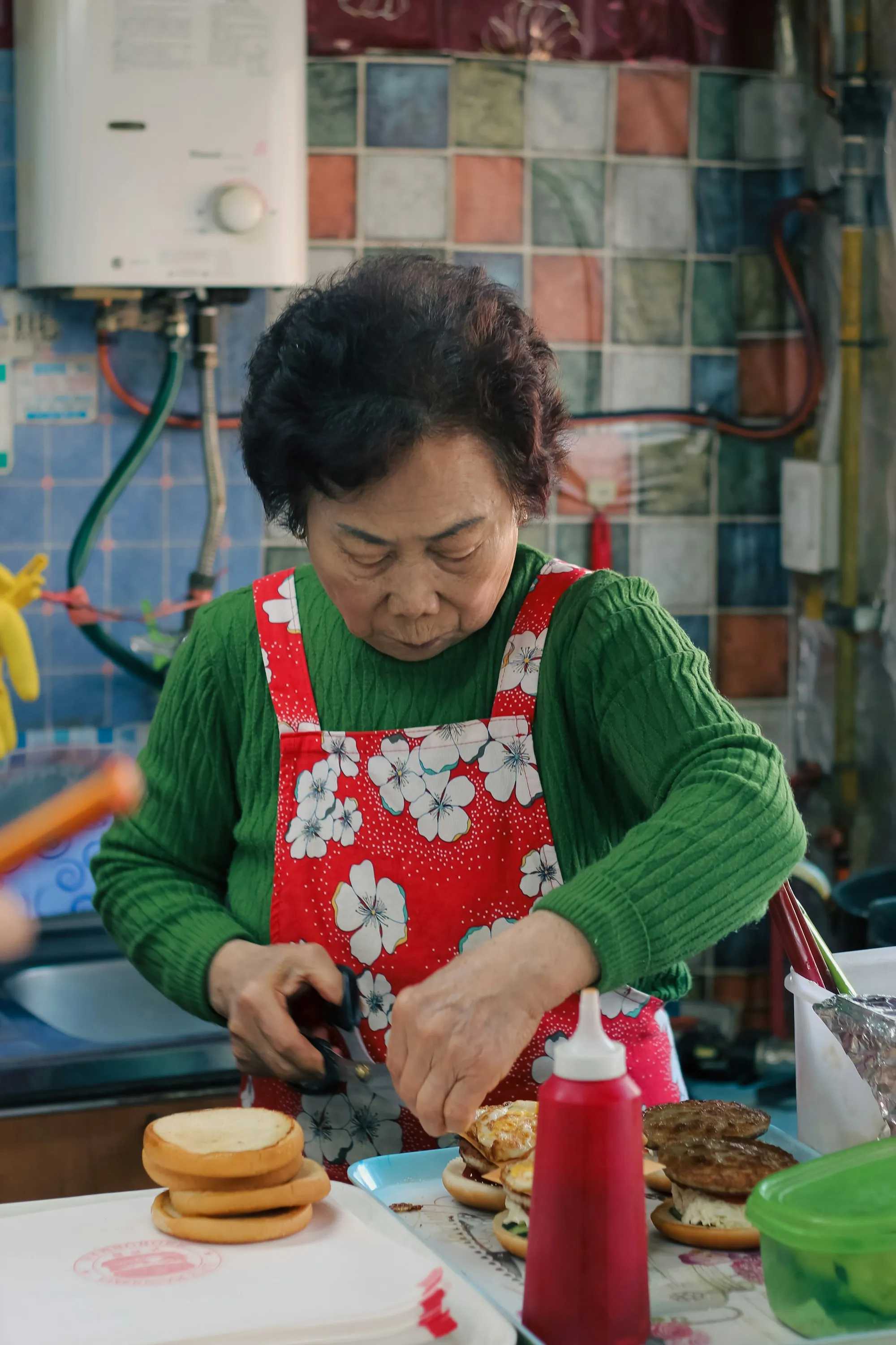 An aide chopping vegetables at a kitchen counter beside a plated meal